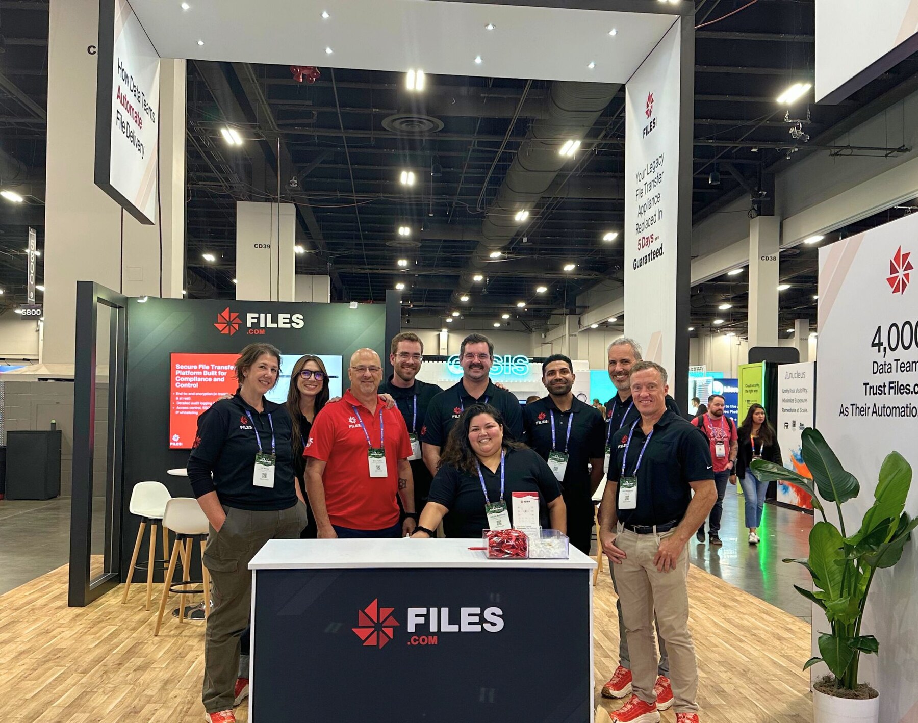 The Files.com team posed at the Gartner conference booth, branded logo banner overhead.