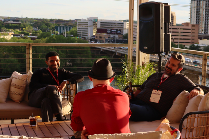 Karan talking with two teammates on a rooftop patio overlooking downtown Austin.
